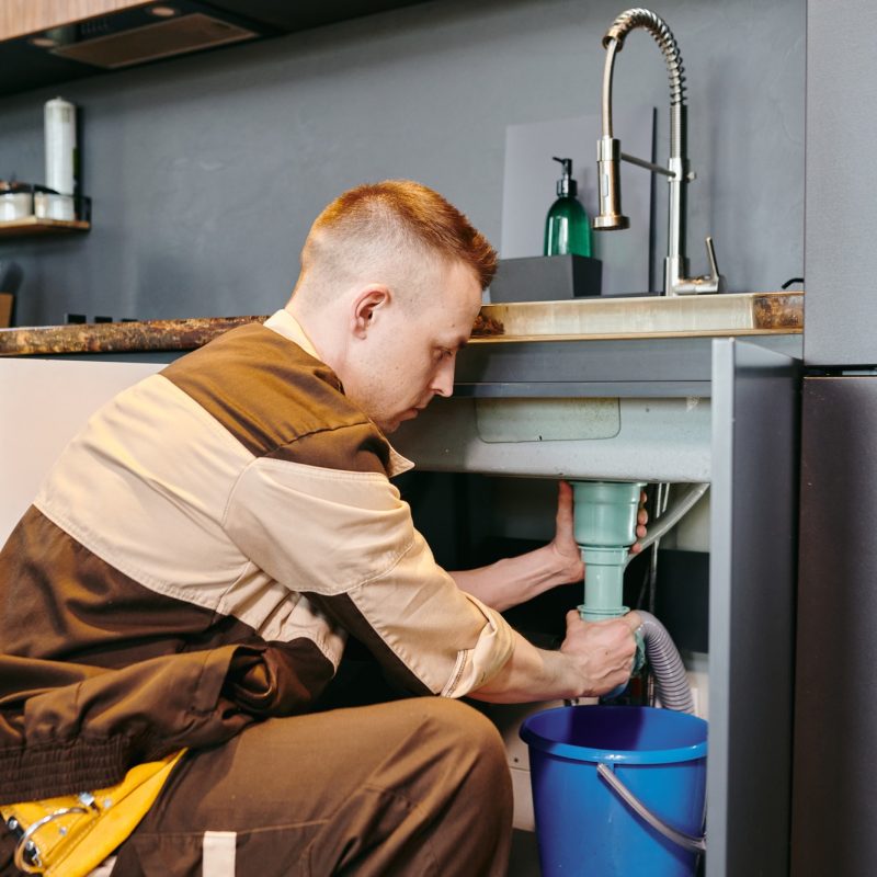 a-man-in-uniform-checking-plumbing-equipment-after-repairing-in-the-kitchen.jpg