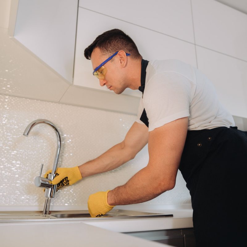 maintenance-man-installing-plumbing-equipment-in-the-kitchen.jpg