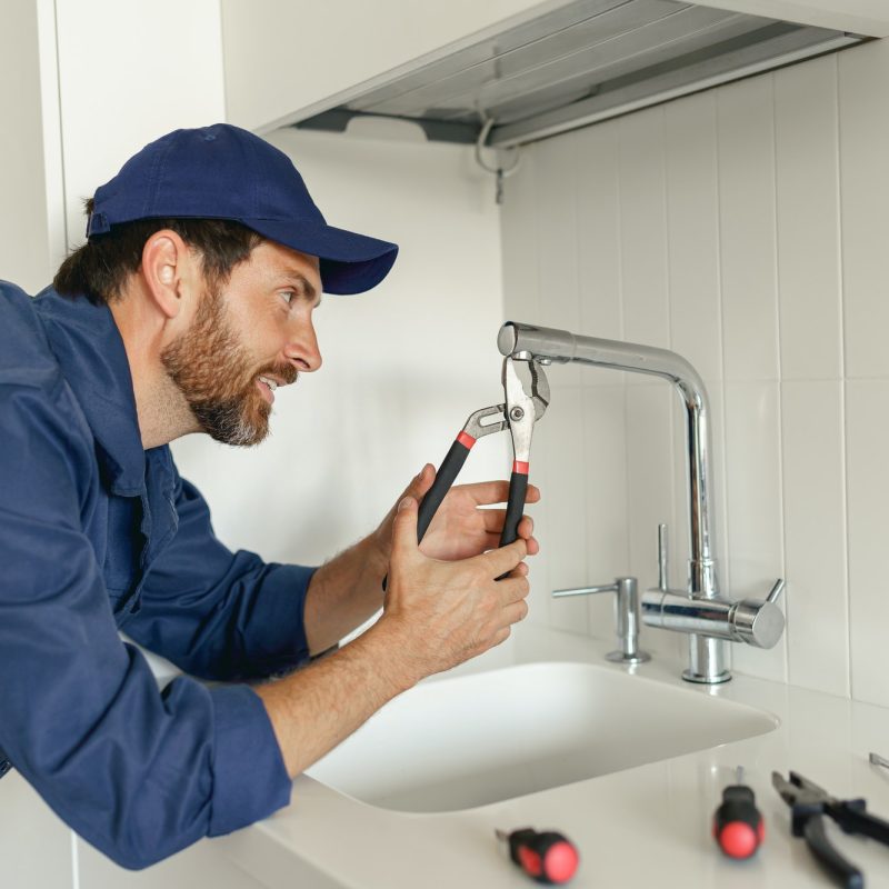 professional-plumber-in-blue-uniform-fixing-broken-water-tap-in-kitchen-repair-service-concept.jpg